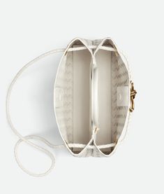 "Find BOTTEGA VENETA East-west Andiamo on Editorialist. Small horizontal Intrecciato leather top handle bag with sliding cross-body strap. Compartmented interior with one zippered pocket, two open pockets. Magnetic closure. Lining: Lambskin bonded Intrecciato. Color: White. Hardware: Brass finish. Height: 18 cm | 7.1\". Width: 29 cm | 11.4\". Depth: 10 cm | 3.9\". Handle drop: 8 cm | 3.15\". Strap drop: 55.5 cm | 21.9\". Lambskin." Designer White Leather Bucket Bag, Luxury White Bucket Bag With Top Handle, High-end Leather Top Handle Bucket Bag, Luxury White Bucket Bag With Top Carry Handle, High-end Leather Bucket Bag With Top Handle, Designer White Bucket Bag With Top Carry Handle, Luxury Bucket Bag With Handle Drop, Luxury Leather Bucket Bag With Round Handle, White Evening Bucket Bag With Top Handle