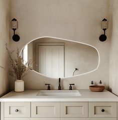 a bathroom with a sink, mirror and vase on the counter top in front of it