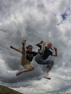 two people jumping in the air with their feet up