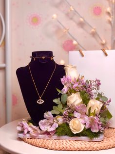 a necklace and flowers on a table with a mannequin in the back ground