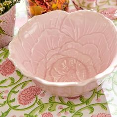 a pink bowl sitting on top of a table next to other vases and flowers