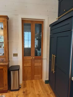 an empty room with wooden floors and two doors on the wall, next to a trash can