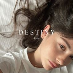 a woman laying on top of a bed next to a white wall with the words destiny