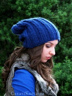 a woman wearing a blue knitted hat with a fur pom - pom