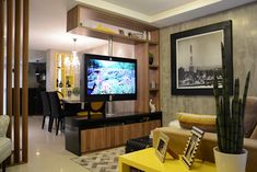 a living room filled with furniture and a flat screen tv mounted on a wall above a yellow table