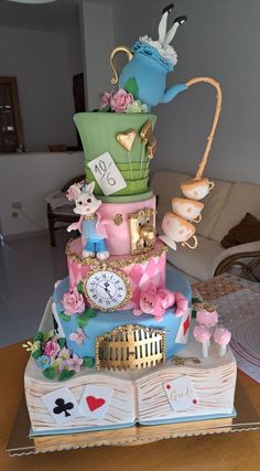 a multi layer cake decorated with pink, blue and green decorations on top of a table