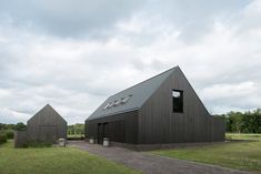 two black barn like structures in the middle of a field