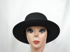 This black wool felt hat has a flat 2 1/2-inch brim and rounded crown. The small/medium will fit 21 to 22 1/2-inch head size, (there is a sizing cord inside the band to adjust to your head size), the large will fit up to 23 1/4 inch head size and the XLG will fit up to 24 1/8 inch head size. This hat is made in a classic vintage Annie Hall style hat and is suitable for any fall and winter weather. Vintage Solid Color Felt Hat With Flat Brim, Vintage Solid Flat Brim Felt Hat, Classic Fur Felt Cloche Hat, Black Wool Top Hat With Short Brim, Classic Solid Color Cloche Felt Hat, Classic Black Fur Felt Cloche Hat, Black Wool Top Hat With Curved Brim, Classic Black Wide Brim Felt Hat, Black Felt Fedora With Short Brim