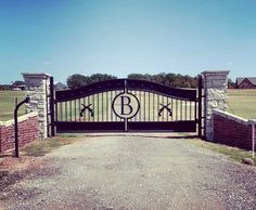 an iron gate with the letter b on it is in front of a brick fence