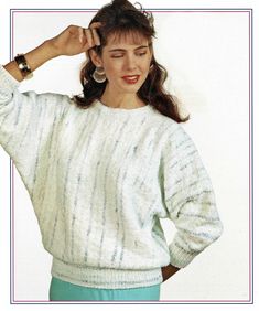 a woman in a white sweater and blue pants with her hands on her head, posing for the camera