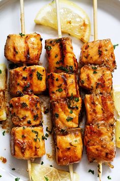 chicken skewers with lemon and parsley on a white plate