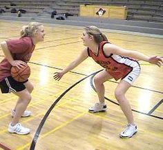 two girls playing basketball on an indoor court