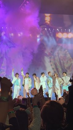 a group of people standing on top of a stage with fireworks in the air behind them