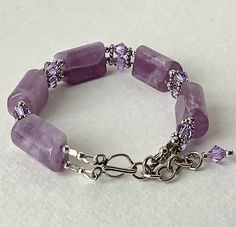 This beautiful lavender quartz bracelet is very elegant ! The five quartz sections are separated by a double row of sterling silver flower spacers, round sterling beads and 6mm violet Swarovski Bicone crystals. They offer a little sparkle against the translucence of the quartz. The bracelet closes with a hook clasp and has a 2 inch chain extender ending in a Swarovski Crystal for a finished appearance. This bracelet is a statement piece that will make a wonderful addition to your jewelry collect Elegant Lavender Bracelets With Faceted Beads, Elegant Lavender Beaded Bracelets With Faceted Beads, Elegant Lavender Beaded Bracelet With Faceted Beads, Elegant Lavender Beaded Bracelets With Gemstone, Elegant Lavender Gemstone Beaded Bracelets, Elegant Handmade Lavender Crystal Bracelet, Elegant Lavender Beaded Bracelet For Healing, Adjustable Lavender Gemstone Beads Bracelets, Adjustable Lavender Bracelet With Gemstone Beads