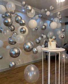 a table with a cake on it in front of some balloons hanging from the ceiling