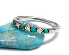 an image of two wedding rings on top of a rock with turquoise and white stones