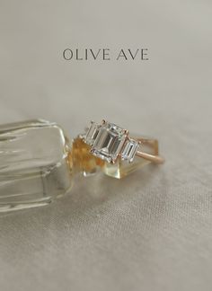 an engagement ring with three baguettes sitting on top of it and the words olive ave written below