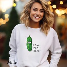 "🥒 \"In A Pickle\" Sweatshirt: A Humorous Twist on Pickle Love 🥒 Get ready to tickle your funny bone with our \"Funny Pickle Sweatshirt,\" featuring a whimsically sad-looking pickle alongside the playful proclamation, \"I am in a pickle.\" This design combines humor with the love for pickles in a unique, eye-catching way. Perfect for those who appreciate a good laugh or find themselves in a pickle more often than not. ⭐ Why You'll Relish This Sweatshirt: ✨ Whimsical Design: The cartoon pickle's expressive face and the clever text create a delightful visual pun that's sure to bring smiles. ✨ Quality and Comfort: Embrace the coziness with our soft, durable Gildan 18000 crewneck, crafted from a 50% cotton and 50% polyester blend for that perfect mix of warmth and breathability. ✨ Pickle Lov Funny Long Sleeve Tops With Text, Funny White Long Sleeve Tops, White Long Sleeve Sweatshirt With Funny Text, Funny Long Sleeve Slogan Tops, Novelty Long Sleeve Cotton Tops, Novelty Cotton Long Sleeve Tops, White Long Sleeve Tops With Funny Text, Cotton Novelty Long Sleeve Tops, Cute Long Sleeve Tops With Funny Text