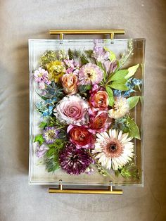 an arrangement of flowers in a square glass box