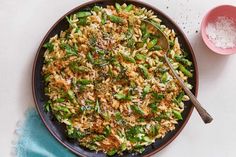 a plate filled with rice and broccoli next to a bowl of seasoning