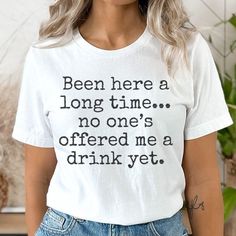 This funny drinking shirt for parties is perfect for anyone impatiently waiting for their drink, featuring the humorous message "Been here a long time...no one's offered me a drink yet." It's a great drinking gift idea, ideal for those who need a drink and want to make it known. 𝐃𝐄𝐓𝐀𝐈𝐋𝐒 🍹 100% Airlume combed and ringspun cotton 🍹 Light fabric (4.2 oz/yd² (142 g/m 🍹 Retail fit 🍹 Tear away label 🍹 Runs true to size 🍹 A unique product designed by the seller and reproduced at scale by a Impatiently Waiting, I Need A Drink, No One, Funny Drinking Shirts, Drinking Gift, Unique Products Design, Wine Shirts, Drinking Humor, Drinking Shirts