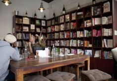 a person sitting at a wooden table in front of a book shelf filled with books