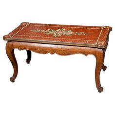 an old wooden table with red and gold paint on the top, sitting against a white background