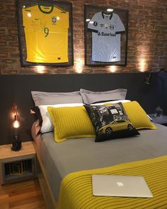 a bed with yellow and gray pillows in front of two framed sports jerseys on the wall