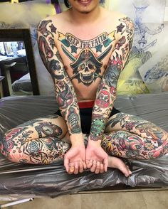 a man with lots of tattoos sitting on top of a bed