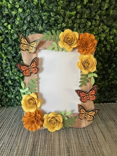 a wooden frame with paper flowers and butterflies