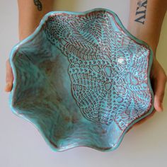 a person holding a blue bowl with designs on it