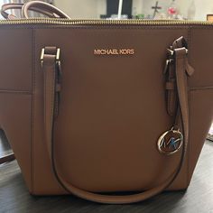 a brown michael kors bag sitting on top of a table