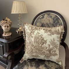 a chair with a pillow on it next to a lamp and a busturine