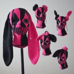 several knitted skull hats are displayed on a stand with pink and black hair in the middle