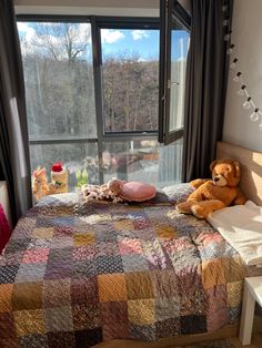 there is a teddy bear sitting on the bed in this room with a window looking out onto the water