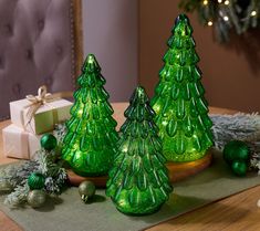 three green glass christmas trees sitting on top of a table