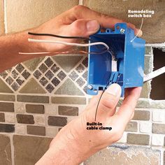 a person is plugging wires into a wall with a blue box attached to it