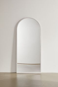 an arched white mirror on the wall in front of a plain white wall and floor