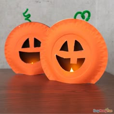 two pumpkin shaped candles sitting on top of a wooden table