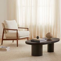 a living room with two chairs and a coffee table in front of a curtained window