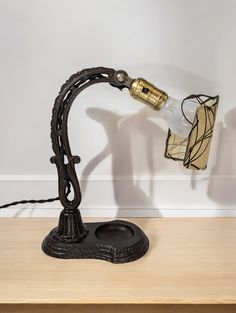 a table lamp with a glass bottle on it's arm and an iron base