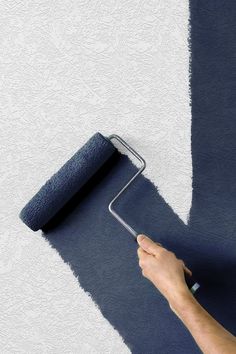 a person using a paint roller on a blue and white wall with a gray rug