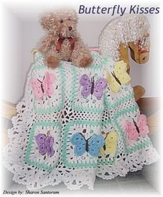 a teddy bear sitting on top of a crocheted blanket next to a stuffed animal