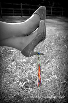 a person's feet with an umbrella hanging from the tip of their shoe, in black and white