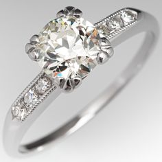 This timeless vintage engagement ring is centered with an old European cut diamond weighing 1.02 carats and set into a four-prong head. The shoulders of the ring are each accented with three (3), channel set, round single cut diamonds, bordered with milgrain edging. The ring measures 6.7mm at the top, rises 6.3mm above the finger, tapering to 1.3mm wide and 1.1mm thick at the base of the shank. The ring is currently a size 7.25 and we offer complimentary resizing to fit. Classic Cushion Cut Diamond Ring With Single Cut Diamonds, Gia Certified Vintage Ring With Round Band, Vintage Cushion Cut Diamond Ring With Single Cut Diamonds, Classic Asscher Cut Ring With Single Cut Diamonds, Classic Asscher Cut Rings With Single Cut Diamonds, Classic White Cushion Cut Wedding Ring, Classic Gia Certified Cushion Cut Rings, Vintage Gia Certified White Diamond Ring, Vintage Gia Certified Diamond Ring