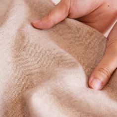 a person's hand on top of a tan cloth