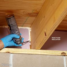 a man in blue gloves holding a drill and nailing the bottom of a wooden structure