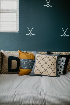 a bed with several pillows on it and two crossed swords painted on the wall behind them