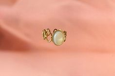 The ring is made from an original ring and a mother-of-pearl stone. The stone is oval and has a dimension of 1cm x 0.8 cm. The ring has a diameter of 1.6mm in diameter. Mother-of-pearl is a stone that produces calm, it has a beneficial effect on emotions and promotes the circulation of energy. It is adjustable to fit all fingers. My jewelry is handmade from materials and fine stones carefully selected in my workshop in Paris. Each stone is natural and unique and may therefore have color variatio Elegant Mother Of Pearl Ring As Gift, Elegant Mother Of Pearl Ring For Gift, Elegant Brass Moonstone Ring, Vintage Pearl Ring With Gemstone, Elegant Opal Ring With Moonstone, Round Metal Pearl Ring As Gift, Gold Mother Of Pearl Ring As A Gift, Handmade Vintage Oval Pearl Ring, Elegant Brass Rings With Cabochon