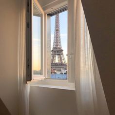 the eiffel tower is seen through an open window in this room with sheer curtains